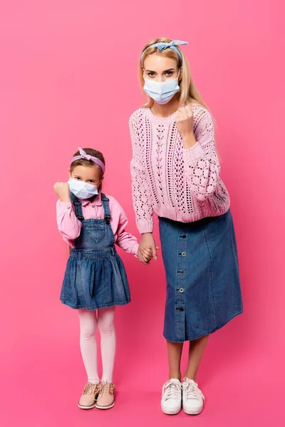 全长的母亲和女儿 戴着口罩 紧握拳头 手牵手 站在粉红上 — 图库照片