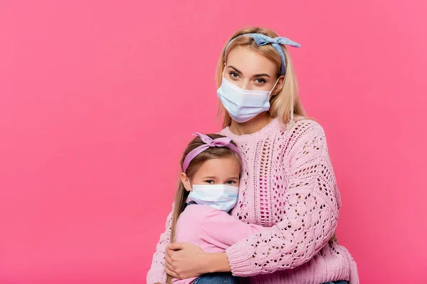 Madre Hija Máscaras Médicas Mirando Cámara Mientras Abraza Aislado Rosa —  Fotos de Stock