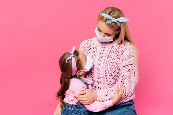 Moeder Dochter Medische Maskers Knuffelen Kijken Naar Elkaar Geïsoleerd Roze — Stockfoto