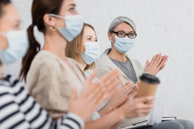 Tıp maskeli Asyalı iş kadını seminer sırasında meslektaşlarını alkışladı 