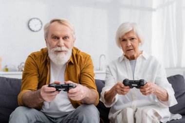 KYIV, UKRAINE - 17 Aralık 2020: Evde video oyunu oynayan yaşlı çift 