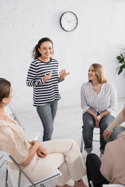 smiling african american speaker standing near group of women during seminar