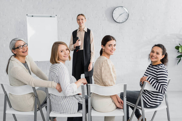 счастливые межрасовые деловые женщины и веселый оратор улыбаясь во время лекции