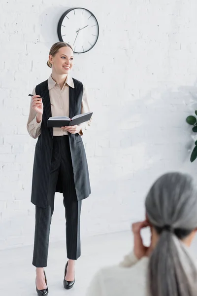 Jonge Spreker Met Notebook Glimlach Buurt Vrouw Tijdens Seminar — Stockfoto