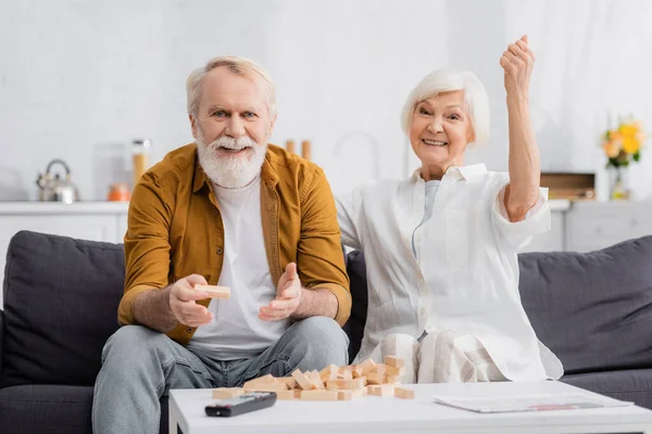 Elderly Man Holding Block Wood Tower Game Wife Showing Yeah — Stock Photo, Image