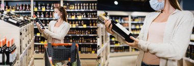 Collage of young woman in medical mask holding bottle of wine near shopping cart in supermarket, banner 
