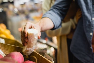 Markette arka planda turp tutan bir adamın görüntüsü bulanık. 