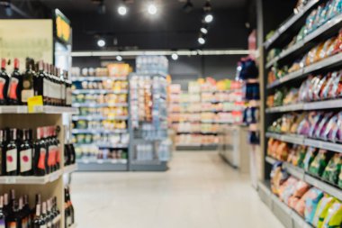 Arka planda bulanık şişeler ve süpermarketteki raflarda yiyecek var. 