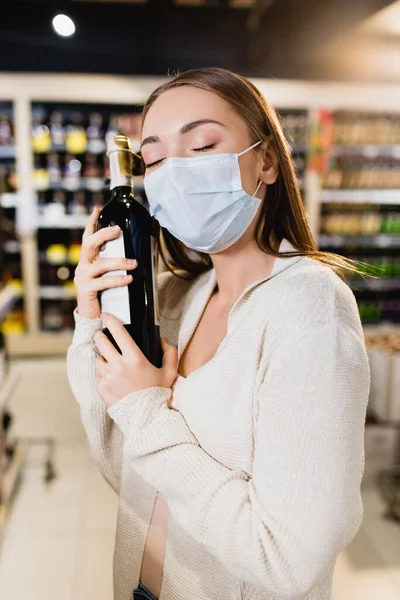 Γυναίκα Ιατρική Μάσκα Αγκαλιάζει Μπουκάλι Κρασί Στο Σούπερ Μάρκετ — Φωτογραφία Αρχείου