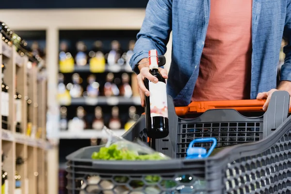 Pemandangan Seorang Pria Menaruh Botol Anggur Keranjang Belanja Latar Depan — Stok Foto