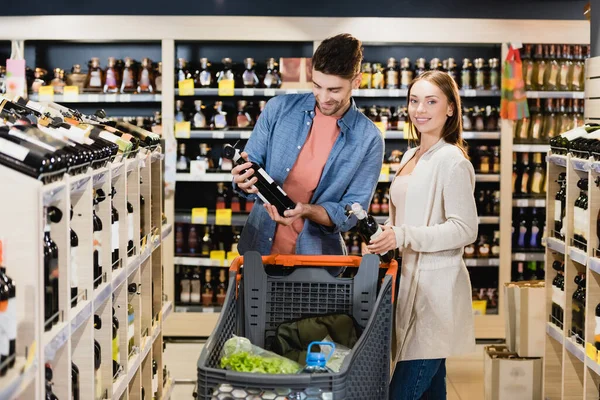 Donna Sorridente Guardando Fotocamera Vicino Fidanzato Con Bottiglia Vino Nel — Foto Stock