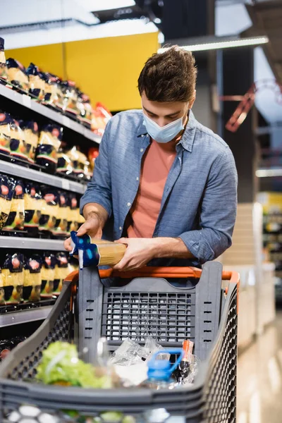 Man Medical Mask Holding Packages Groceries Shopping Cart Blurred Foreground — Stock Photo, Image