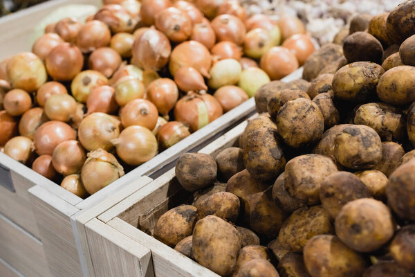 Potatoes and onions on blurred background in supermarket 