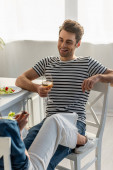 šťastný muž drží sklenici vína a dívá se na ženu v kuchyni 