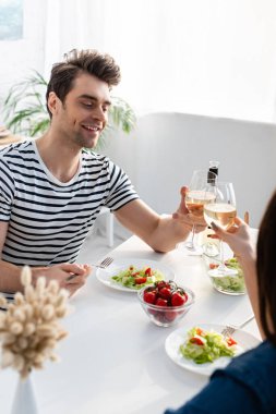 Neşeli adam yemek masasında bir kadınla kadeh kadeh kaldırıyor.