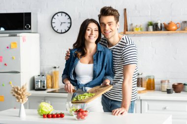 Mutlu çift modern mutfakta salata hazırlıyor.