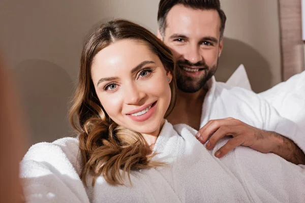 Smiling Woman Looking Camera Boyfriend Bathrobe Blurred Background Hotel — Stock Photo, Image