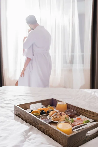 Breakfast Wooden Tray Bed Couple Bathrobes Embracing Window Blurred Background — Stock Photo, Image