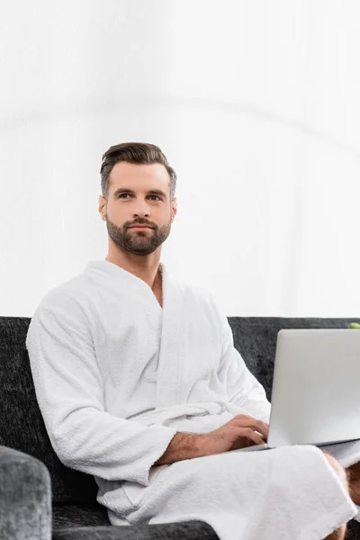 Bearded Man Bathrobe Using Laptop Blurred Foreground Hotel — Stock Photo, Image