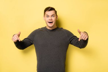 Heyecanlı adam sarı arka planı işaret ediyor.