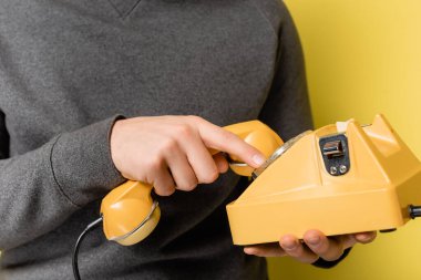 Cropped view of man using retro telephone on yellow background clipart