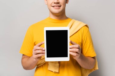 Gri arkaplanda boş ekranlı dijital tablet tutan adamın kırpılmış görünümü