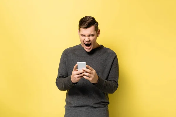 Раздражённый Мужчина Кричит Время Использования Мобильного Телефона Жёлтом Фоне — стоковое фото