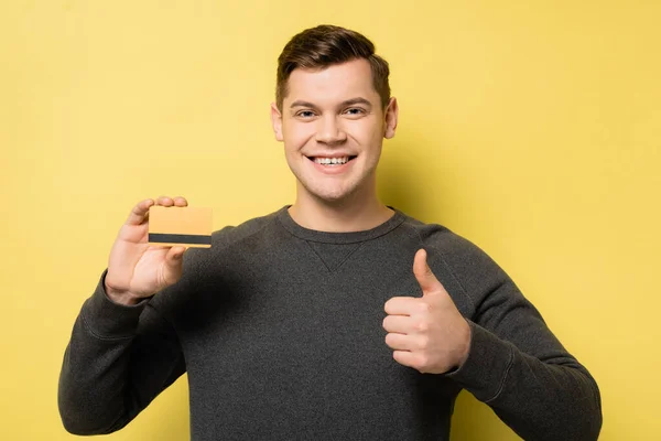 Uśmiechnięty Mężczyzna Pokazując Jak Karta Kredytowa Żółtym Tle — Zdjęcie stockowe