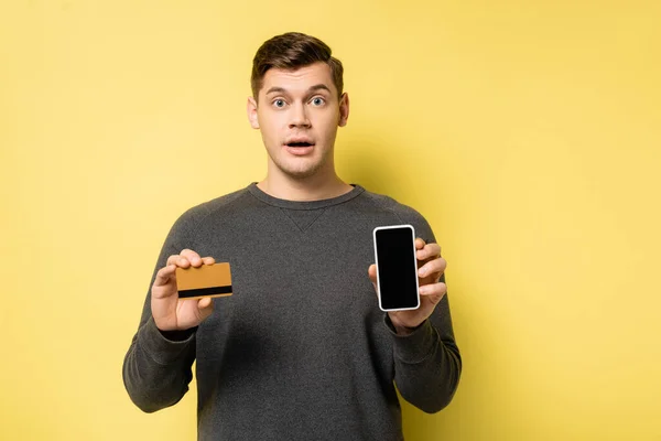 Niesamowity Człowiek Trzyma Kartę Kredytową Smartfona Żółtym Tle — Zdjęcie stockowe
