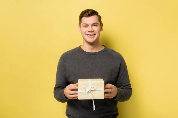 Smiling Man Gift Box Looking Camera Yellow Background — Stock Photo, Image