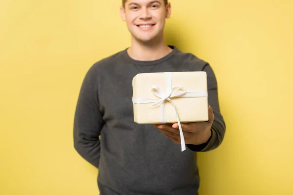 Caja Regalo Mano Del Hombre Sonriente Borrosa Sobre Fondo Amarillo — Foto de Stock