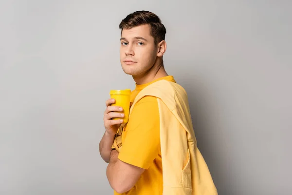 Man Looking Camera While Holding Yellow Takeaway Coffee Grey Background — Stock Photo, Image