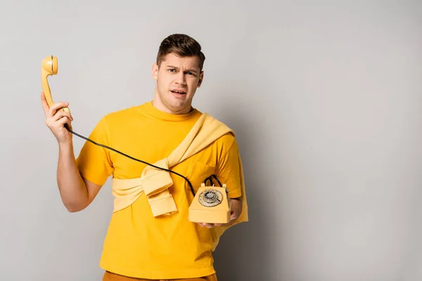 Embarrassed Man Holding Yellow Retro Telephone Grey Background — Stock Photo, Image