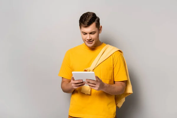 Homem Sorridente Camiseta Amarela Usando Tablet Digital Fundo Cinza — Fotografia de Stock