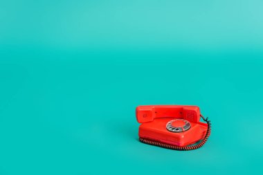 bright red vintage telephone on turquoise background with copy space clipart