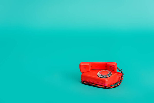 bright red vintage telephone on turquoise background with copy space