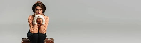 Жінка Капелюсі Ретро Одязі Дивиться Камеру Сидячи Старовинній Валізі Сірому — стокове фото