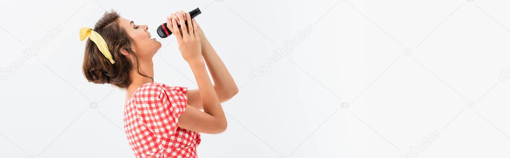 side view of pin up woman singing with microphone isolated on white, banner