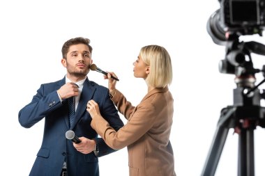 broadcaster adjusting tie while makeup artist powdering his face isolated on white, blurred foreground clipart
