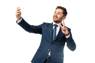 Neşeli iş adamı zafer jesti sergiliyor ve beyazın üstünde selfie çekiyor.