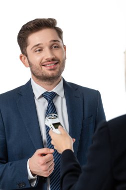 smiling businessman giving interview to journalist with dictaphone isolated on white, blurred foreground clipart