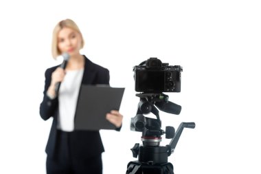 blurred anchorwoman with microphone and clipboard near digital camera isolated on white clipart