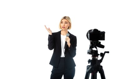 sad anchorwoman with microphone pointing with hand near digital camera on blurred foreground isolated on white clipart