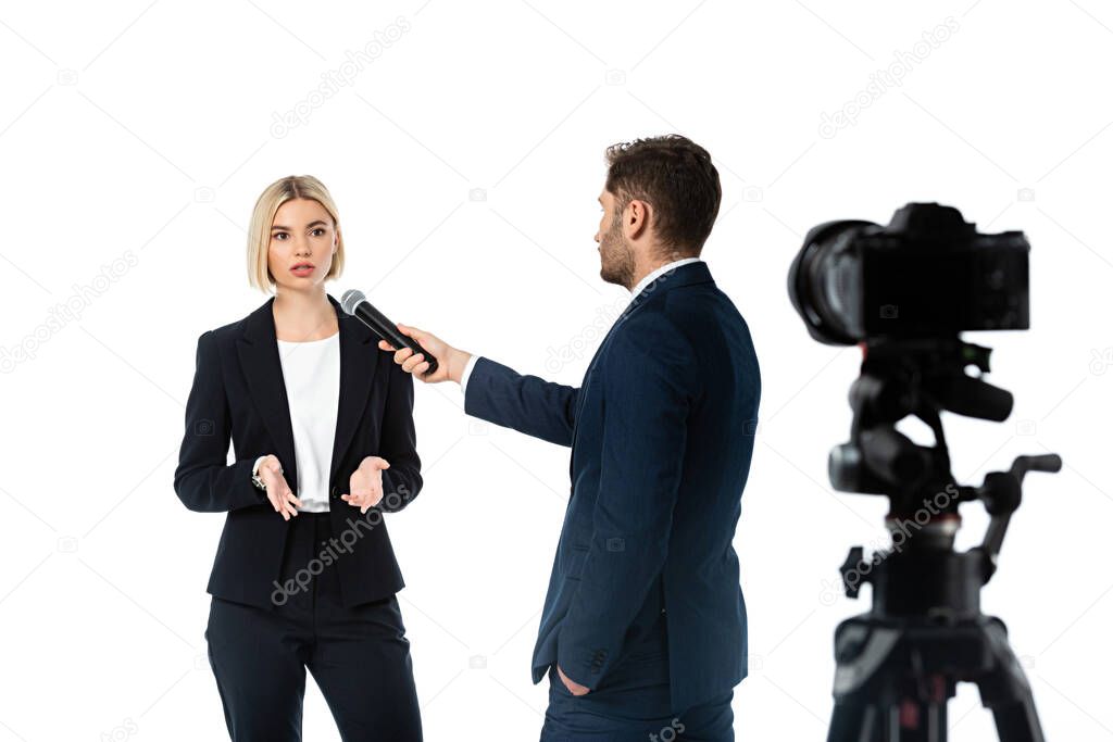 anchorman with hand in pocket taking interview form blonde businesswoman isolated on white, blurred foreground