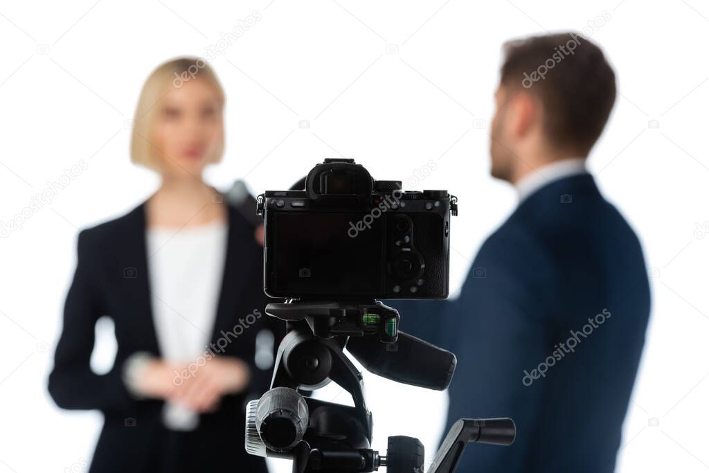 selective focus of digital camera near couple of news anchors on blurred background isolated on white