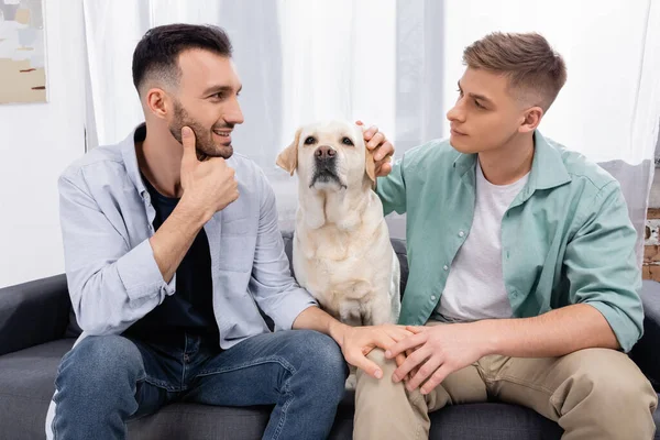 Couple Homosexuel Regardant Autre Près Labrador Dans Salon — Photo