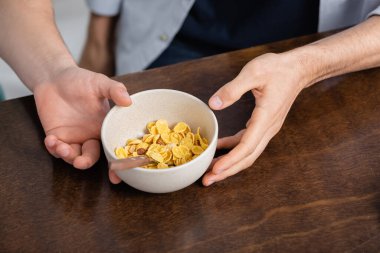 cropped view of homosexual men holding bowl with corn flakes  clipart