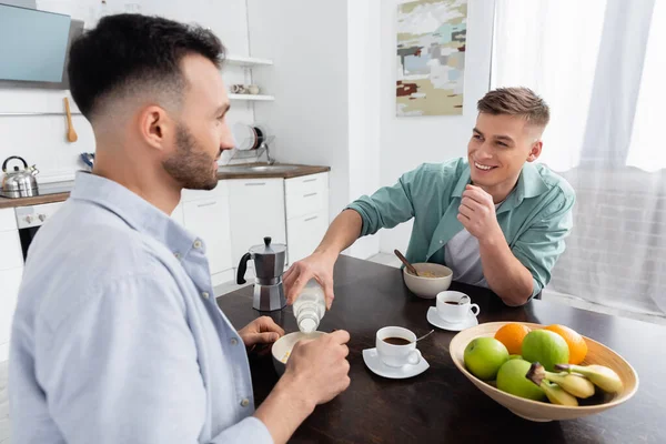 Feliz Hombre Homosexual Vertiendo Leche Tazón Con Hojuelas Maíz Cerca — Foto de Stock