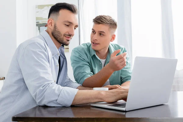 Homosexual Man Gesturing While Looking Husband Using Laptop — Stock Photo, Image