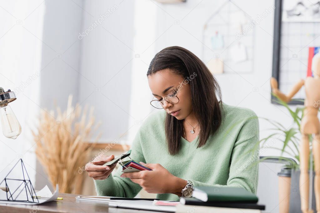 african american interior designer choosing color of material, blurred foreground